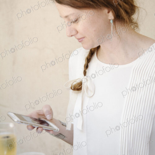 Portrait of a woman with long auburn hair in a braid, looking at her cell phone.