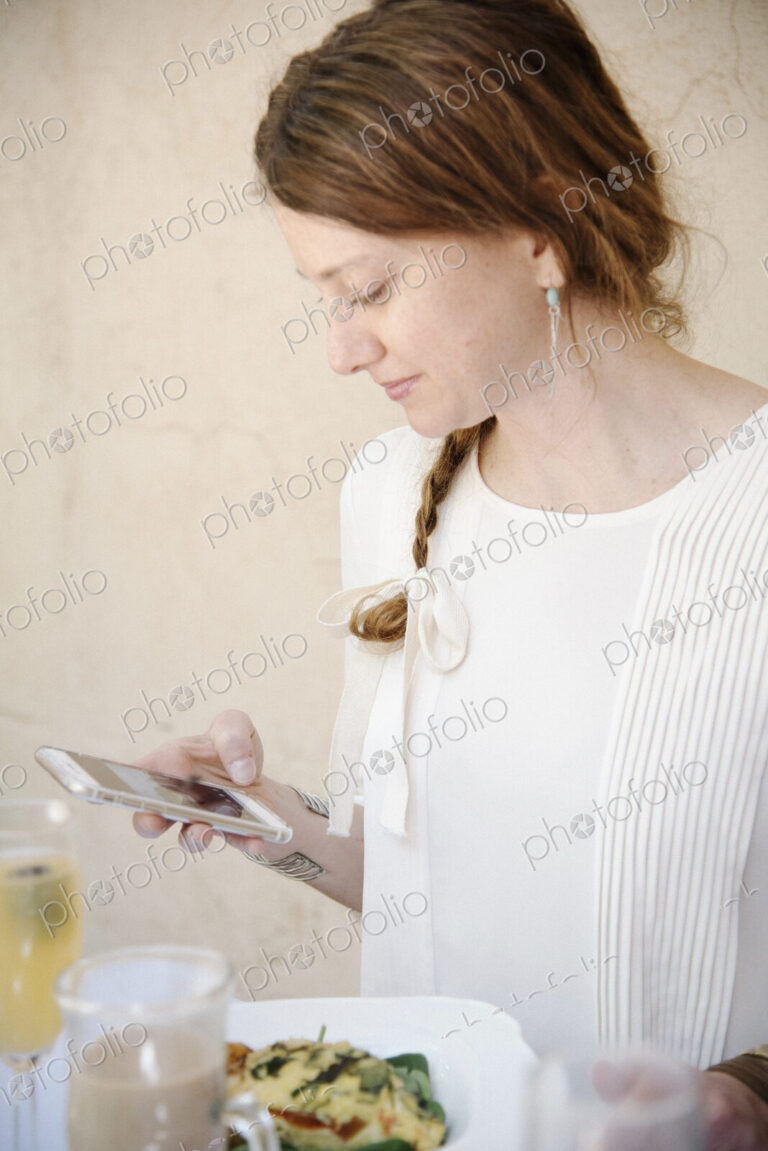 Portrait of a woman with long auburn hair in a braid, looking at her cell phone.