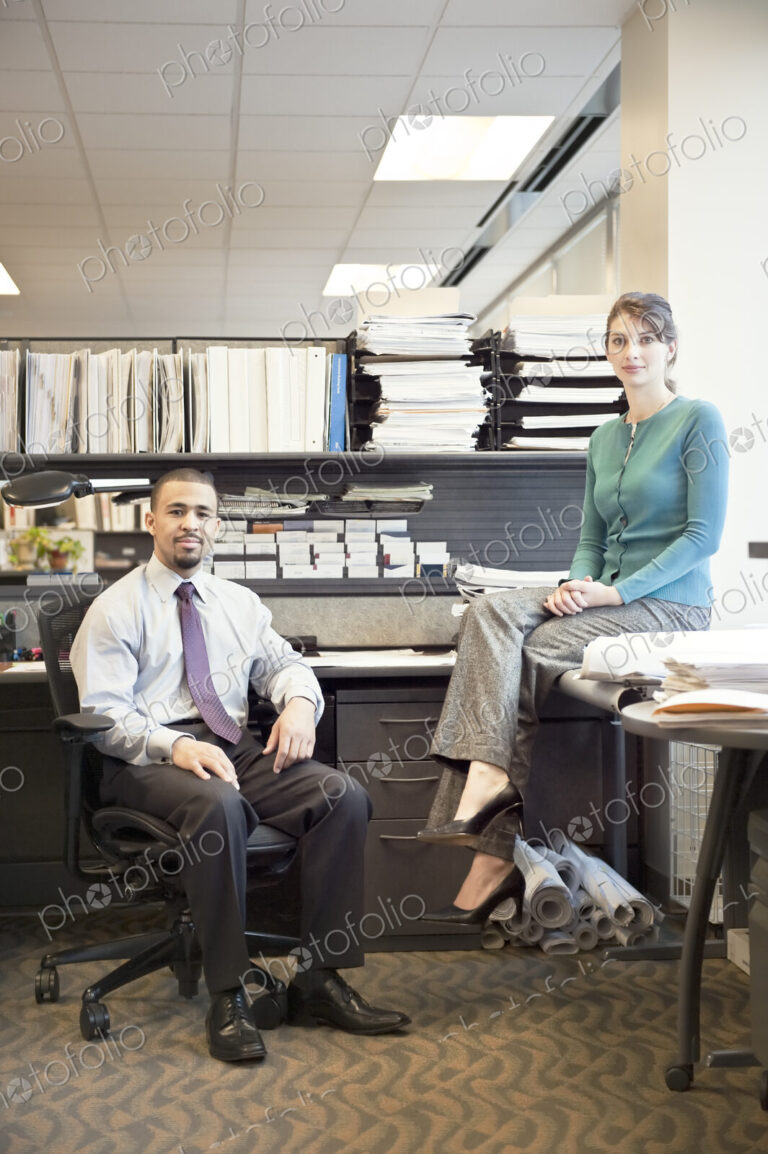 Portrait of a young Black businessman and Caucasian businesswoman in an office cubicle.