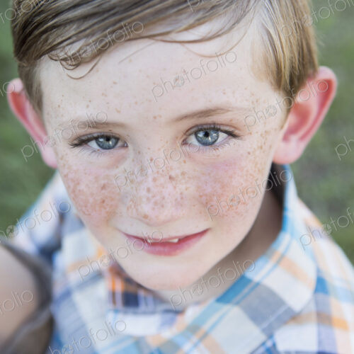 Portrait of a young boy with blue eyes and freckles on his nose.