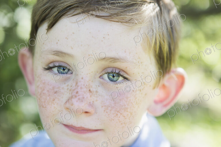 Portrait of a young boy with red hair, blue eyes and freckles on his nose.