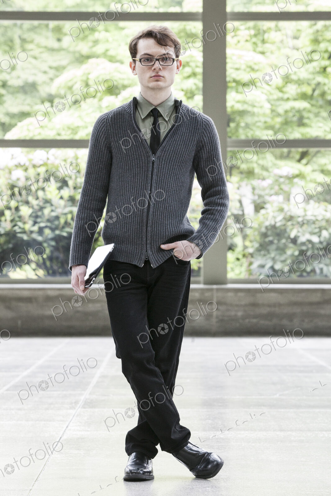 Portrait of a young hip geek businesman holding a notebook computer.