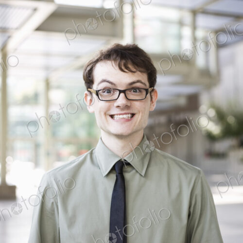 Portrait of a young hip geek businesman standing in the lobby of a convention center. Portrait of a young hip geek businesman standing in the lobby of a convention center.