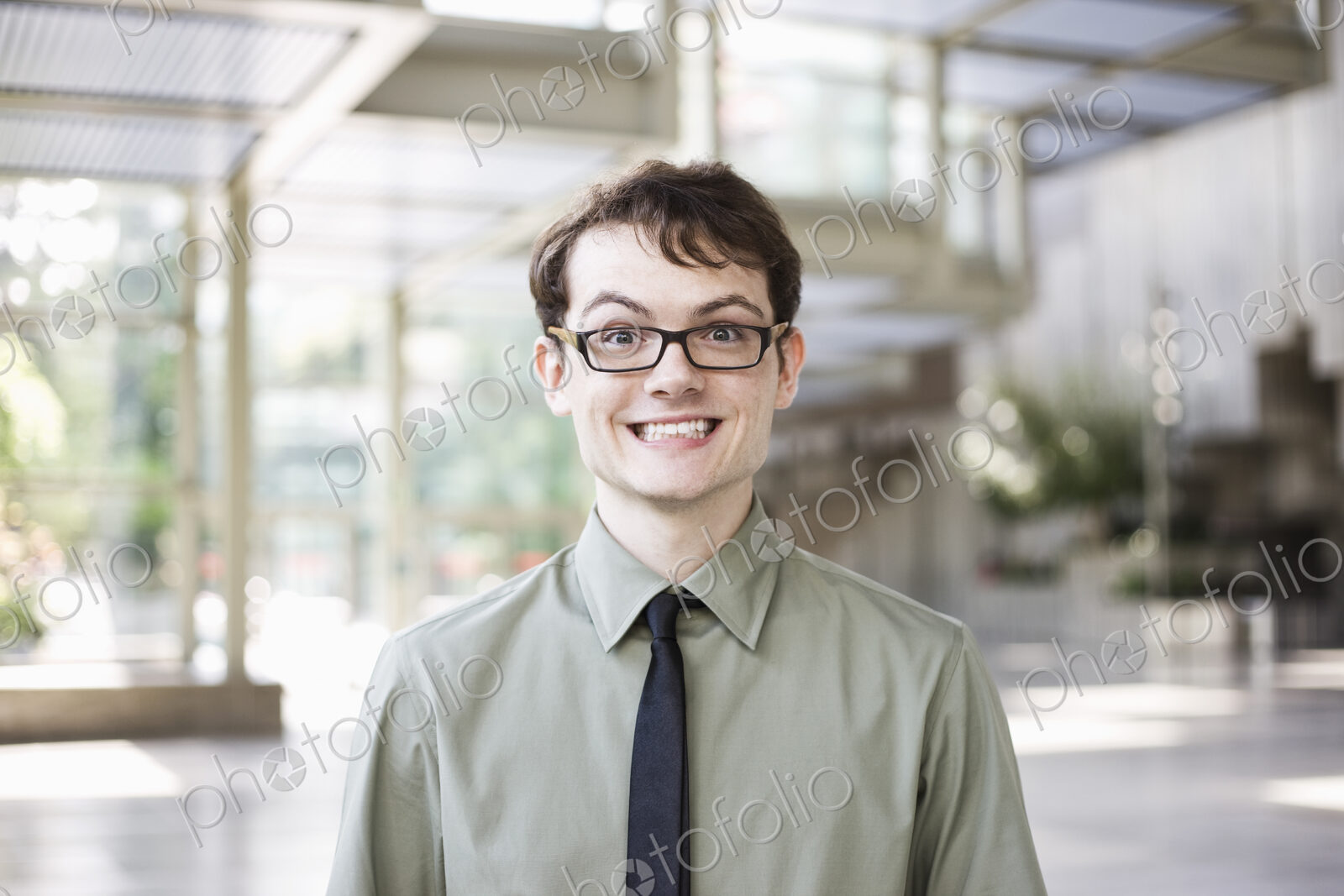 Portrait of a young hip geek businesman standing in the lobby of a convention center.