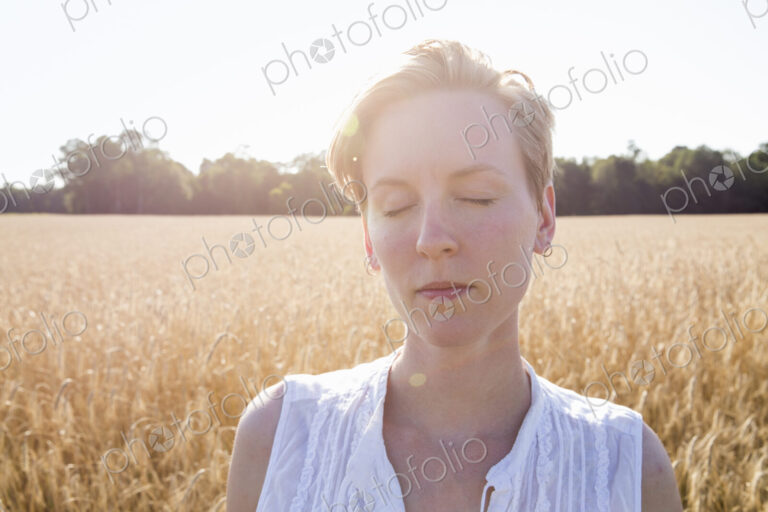 Portrait of a young woman standing in a cornfield.