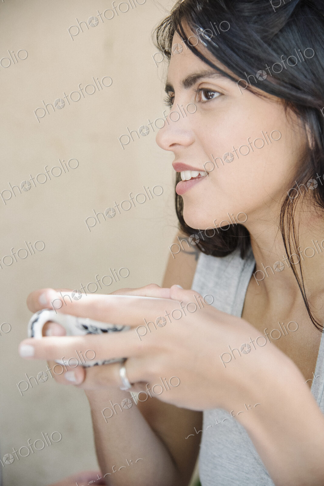 Portrait of a young woman with long brown hair holding a cup.