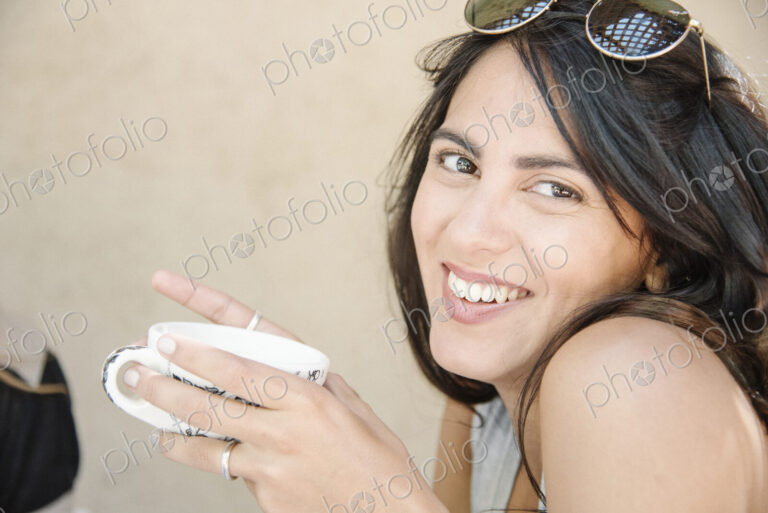 Portrait of a young woman with long brown hair holding a cup.