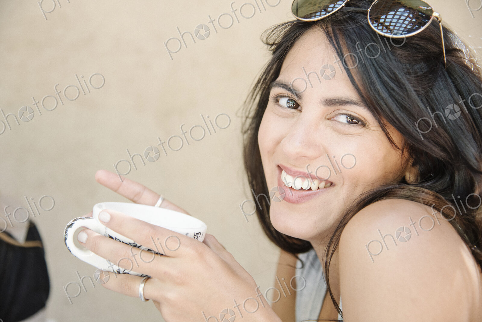 Portrait of a young woman with long brown hair holding a cup.