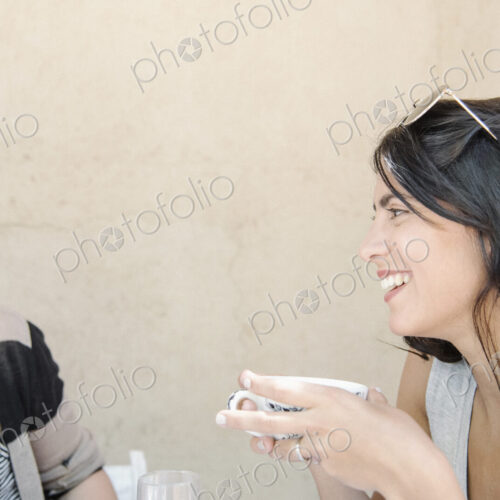 Portrait of a young woman with long brown hair holding a cup, chatting to a friend. Portrait of a young woman with long brown hair holding a cup, chatting to a friend.