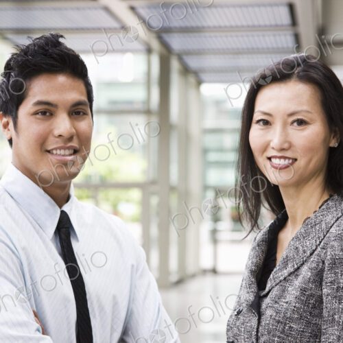 Portrait of an Asian businesswoman and a businessman in the lobby of a convention center. Portrait of an Asian businesswoman and a businessman in the lobby of a convention center.