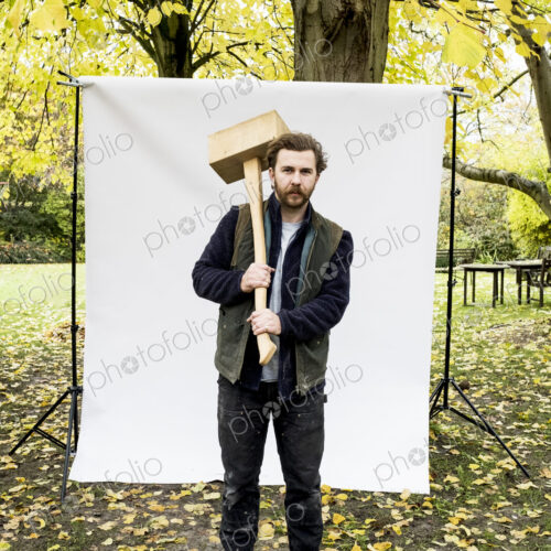 Portrait of bearded man holding wooden block standing in front of white background in… Portrait of bearded man holding wooden block standing in front of white background in…
