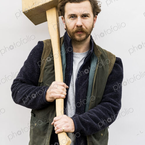 Portrait of bearded man holding wooden block standing in front of white background,… Portrait of bearded man holding wooden block standing in front of white background,…