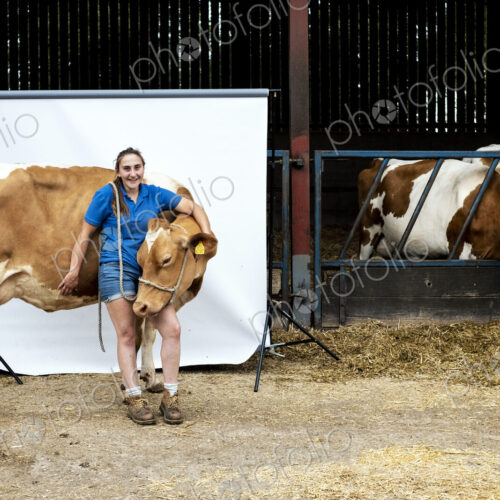 Portrait of female farmer standing in front of a barn with a Guernsey cow. Portrait of female farmer standing in front of a barn with a Guernsey cow.