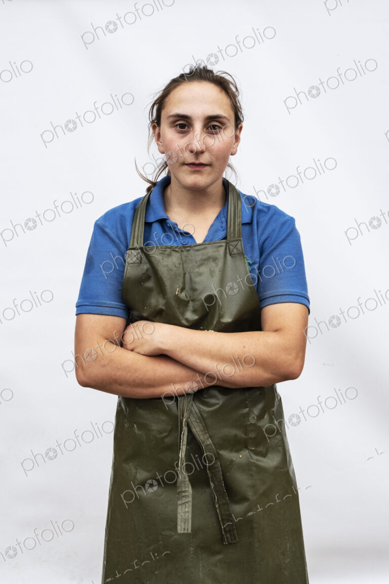 Portrait of female farmer wearing green apron looking at camera.