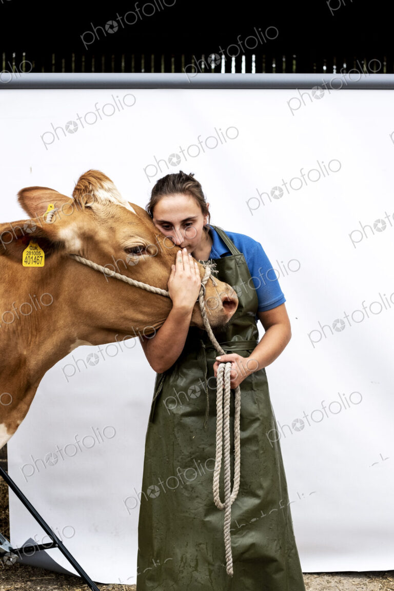 Portrait of female farmer wearing green apron with a Guernsey cow.