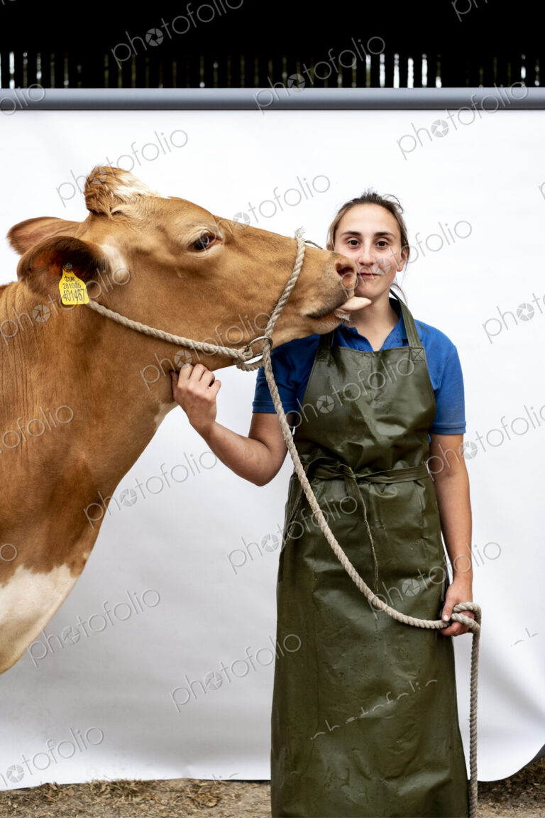 Portrait of female farmer wearing green apron with a Guernsey cow.