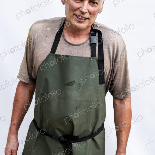 Portrait of male farmer wearing green apron smiling at camera. Portrait of male farmer wearing green apron smiling at camera.