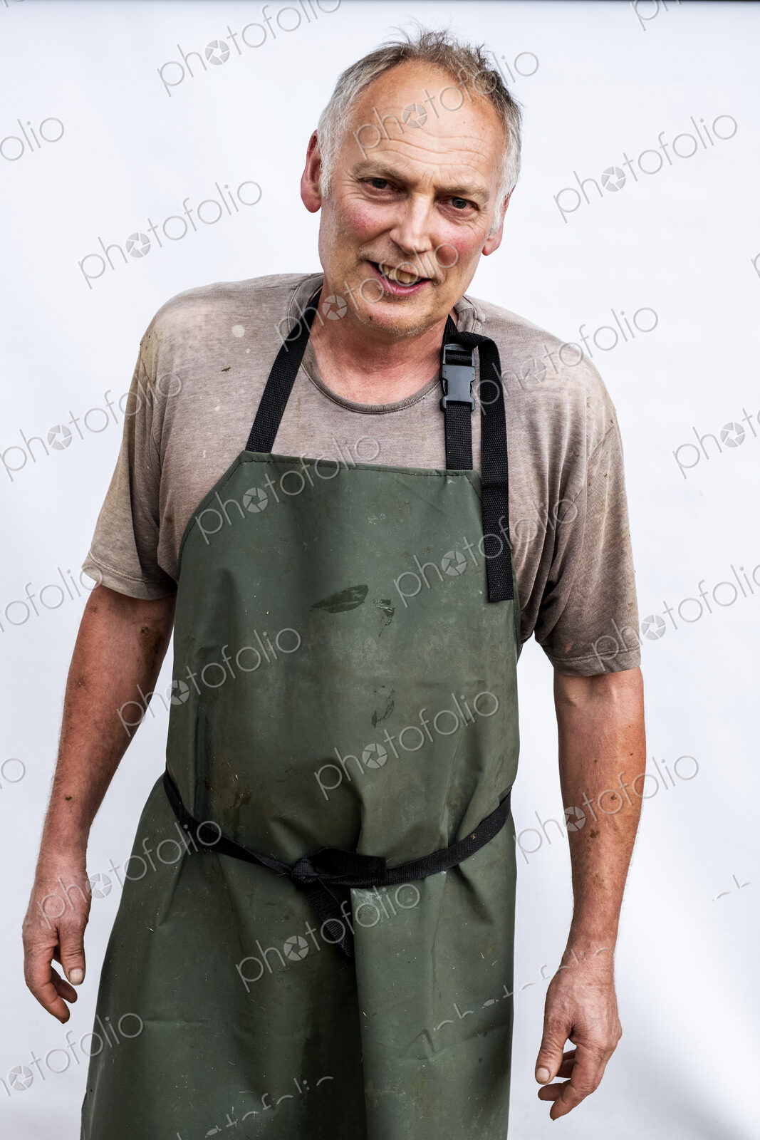 Portrait of male farmer wearing green apron smiling at camera.
