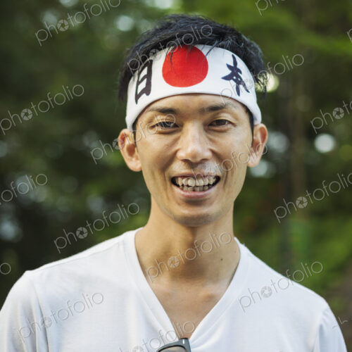 Portrait of man wearing headband with Japanese flag smiling at camera.