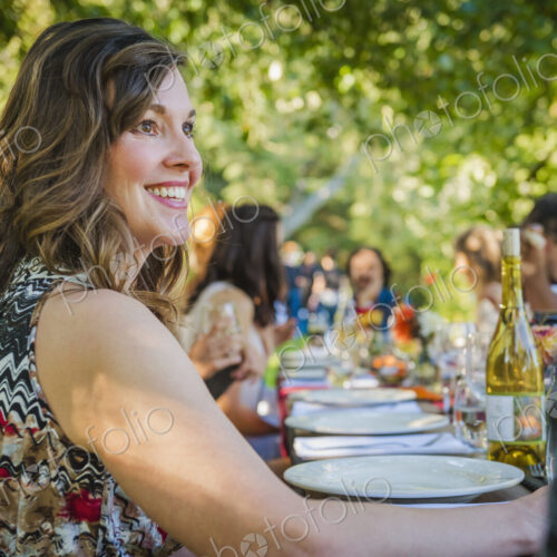 Portrait of smiling Caucasian woman sitting at table at party outdoors Portrait of smiling Caucasian woman sitting at table at party outdoors