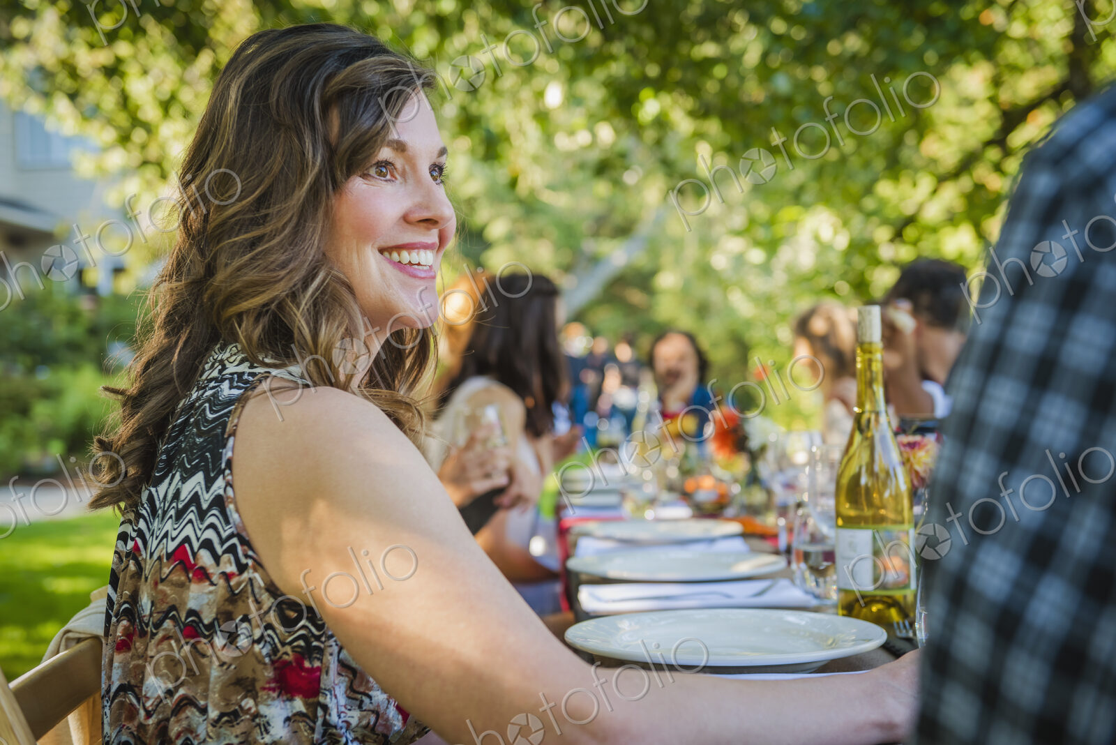 Portrait of smiling Caucasian woman sitting at table at party outdoors