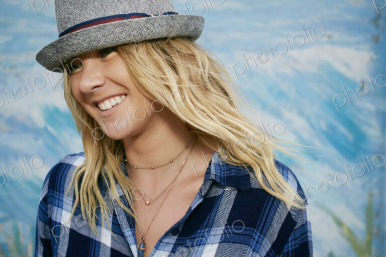 Portrait of smiling woman with long blond hair wearing blue checkered shirt and grey…