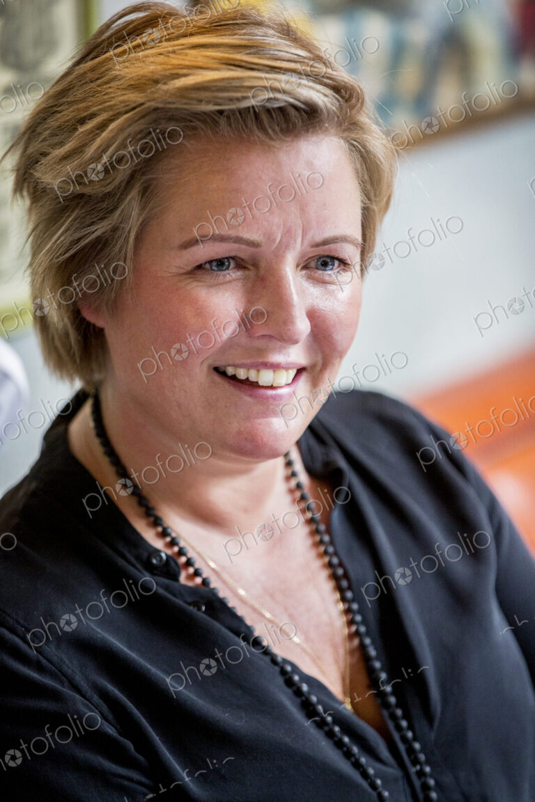 Portrait of smiling woman with short blond hair wearing black top.