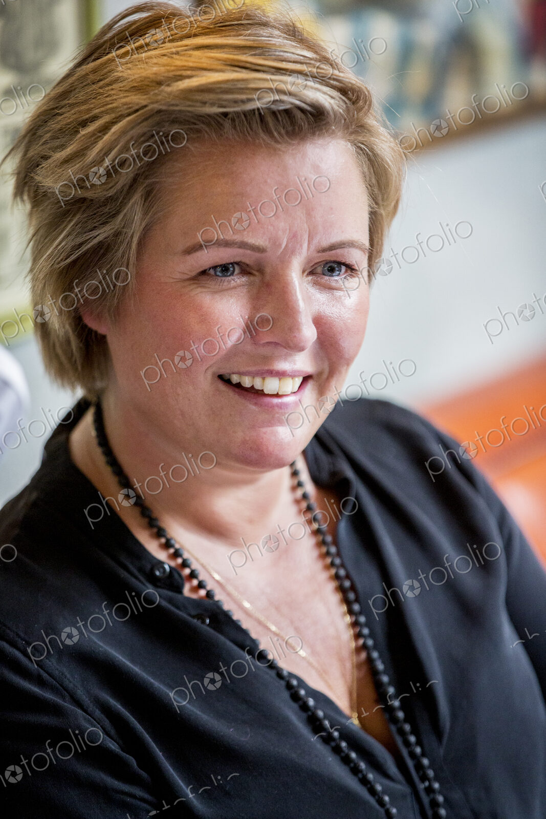 Portrait of smiling woman with short blond hair wearing black top.