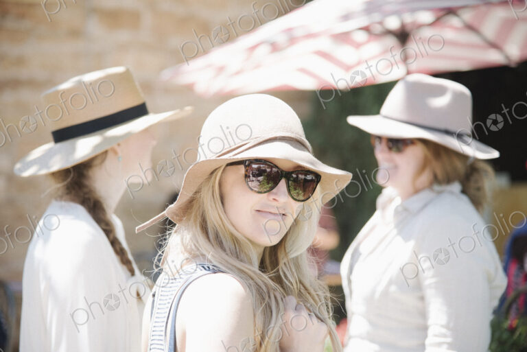 Portrait of three women wearing hats and sunglasses.