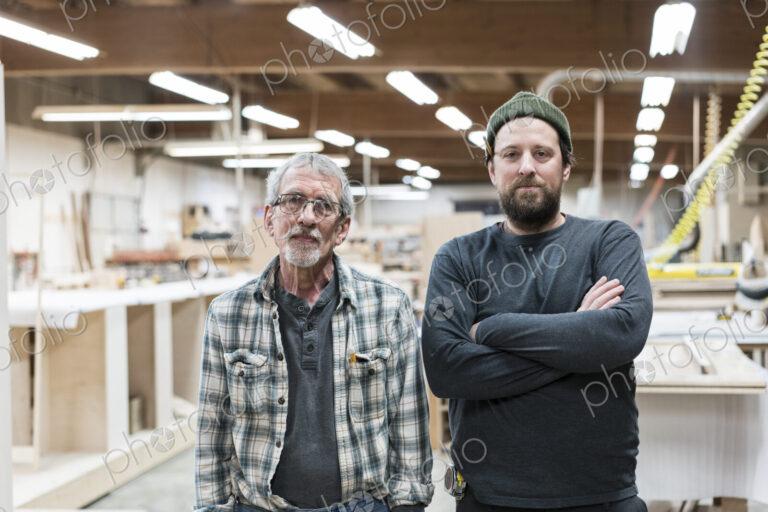 Portrait of two Caucasian carpenters in a large woodworking factory.