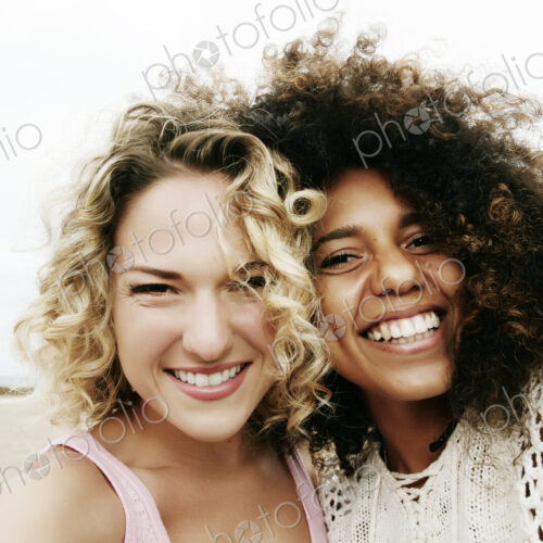 Portrait of two smiling young women with blond and brown curly hair Portrait of two smiling young women with blond and brown curly hair