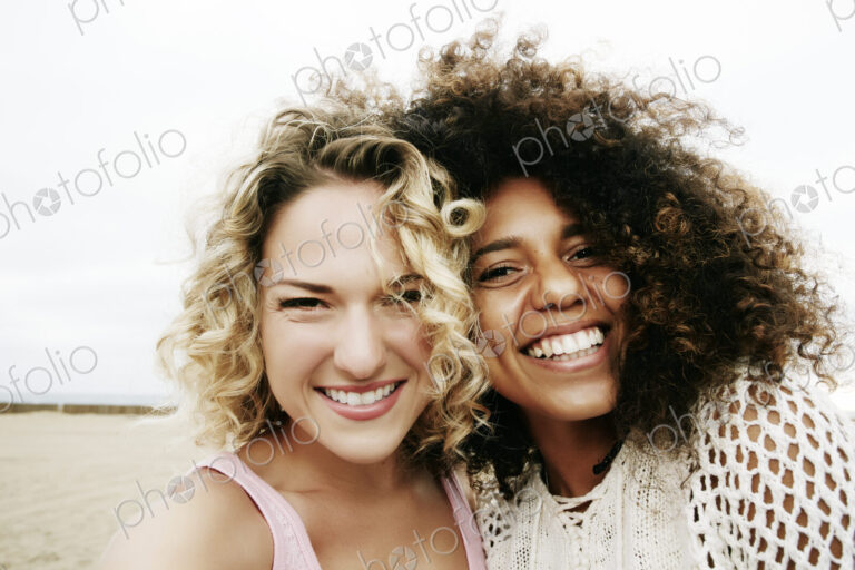 Portrait of two smiling young women with blond and brown curly hair