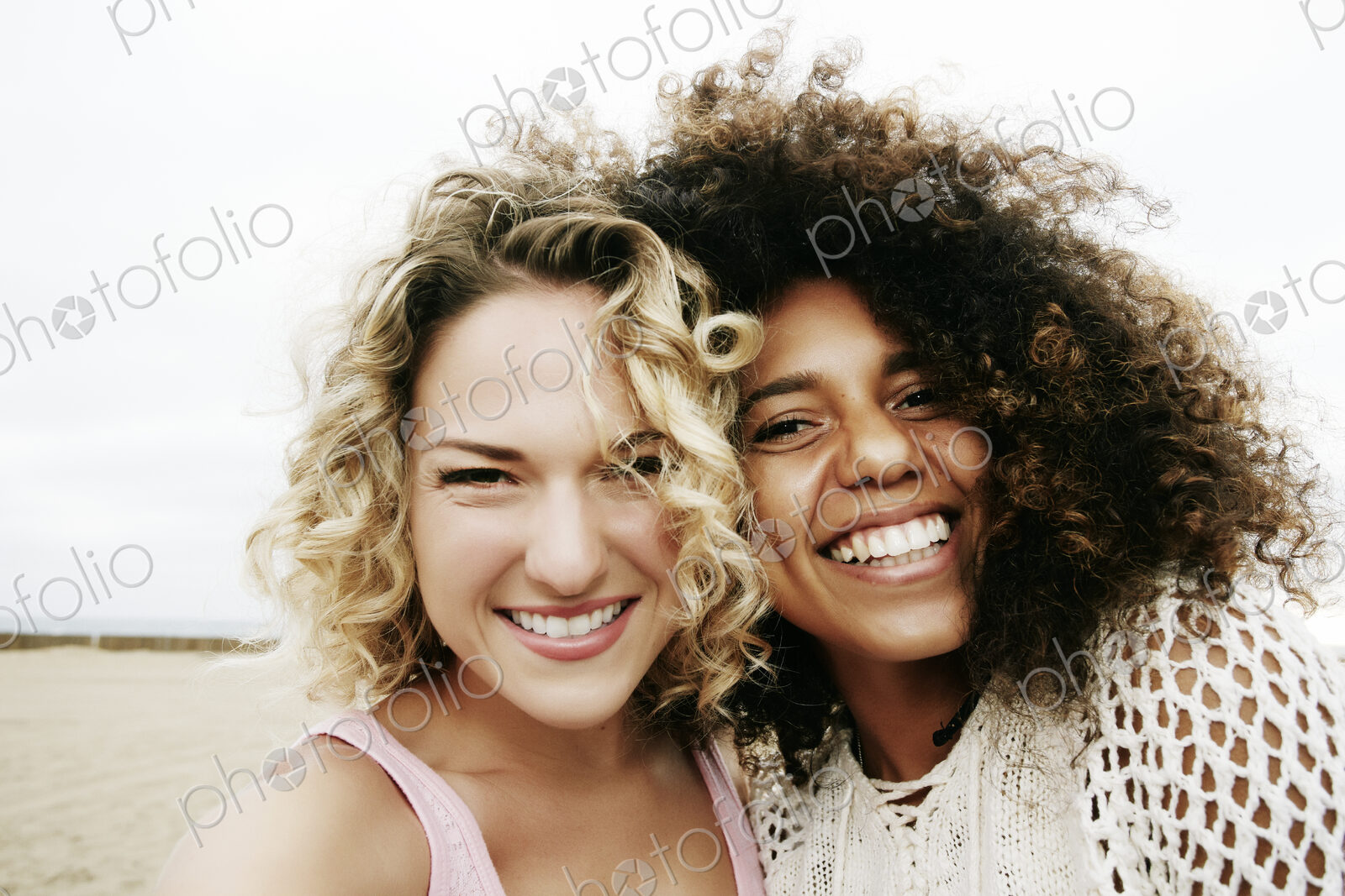 Portrait of two smiling young women with blond and brown curly hair