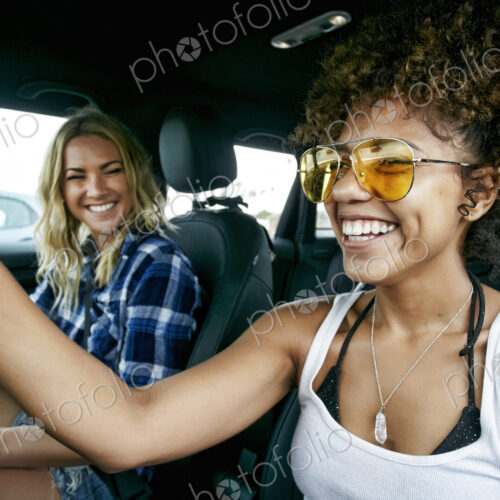 Portrait of two women sitting in car, wearing sunglasses, smiling. Portrait of two women sitting in car, wearing sunglasses, smiling.
