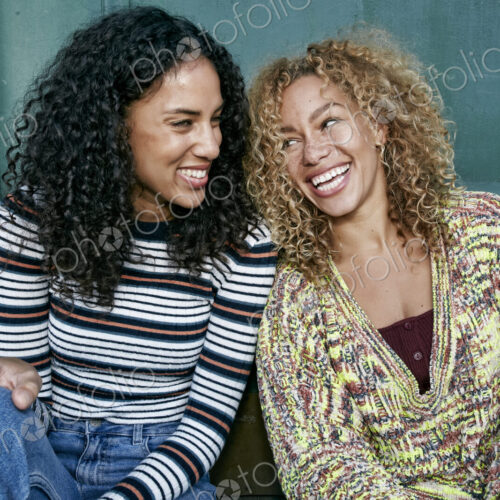 Portrait of two young smiling women with long curly black and blond hair, smiling and… Portrait of two young smiling women with long curly black and blond hair, smiling and…