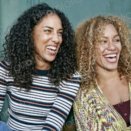 Portrait of two young smiling women with long curly black and blond hair, smiling and… Portrait of two young smiling women with long curly black and blond hair, smiling and…