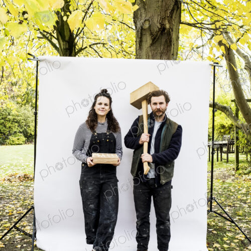 Portrait of woman and bearded man holding wooden blocks standing in front of white… Portrait of woman and bearded man holding wooden blocks standing in front of white…