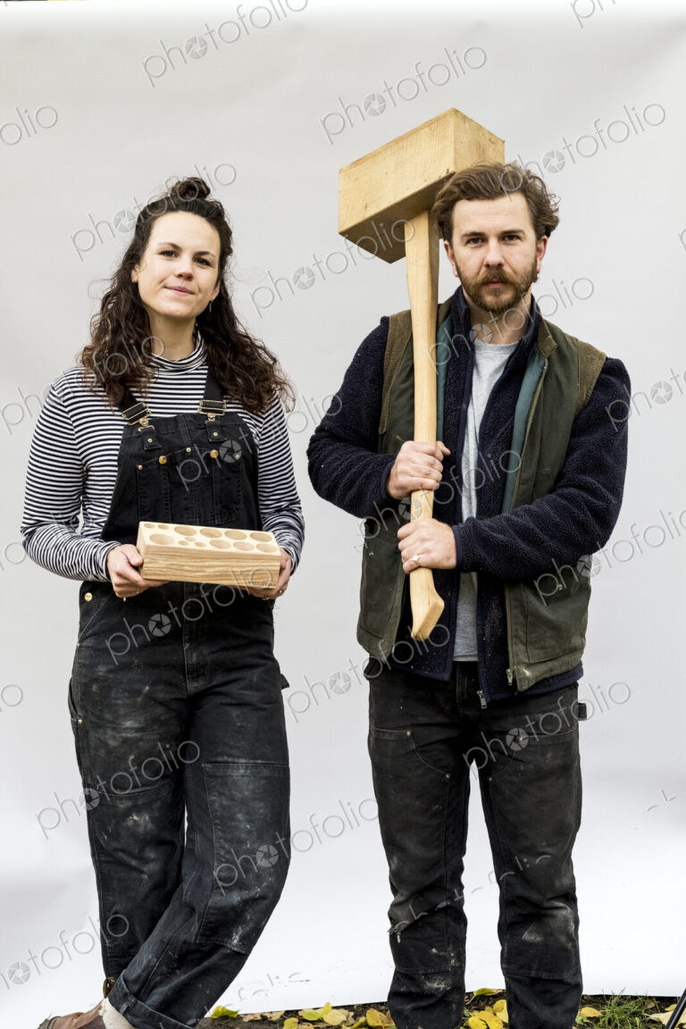 Portrait of woman and bearded man holding wooden blocks standing in front of white…