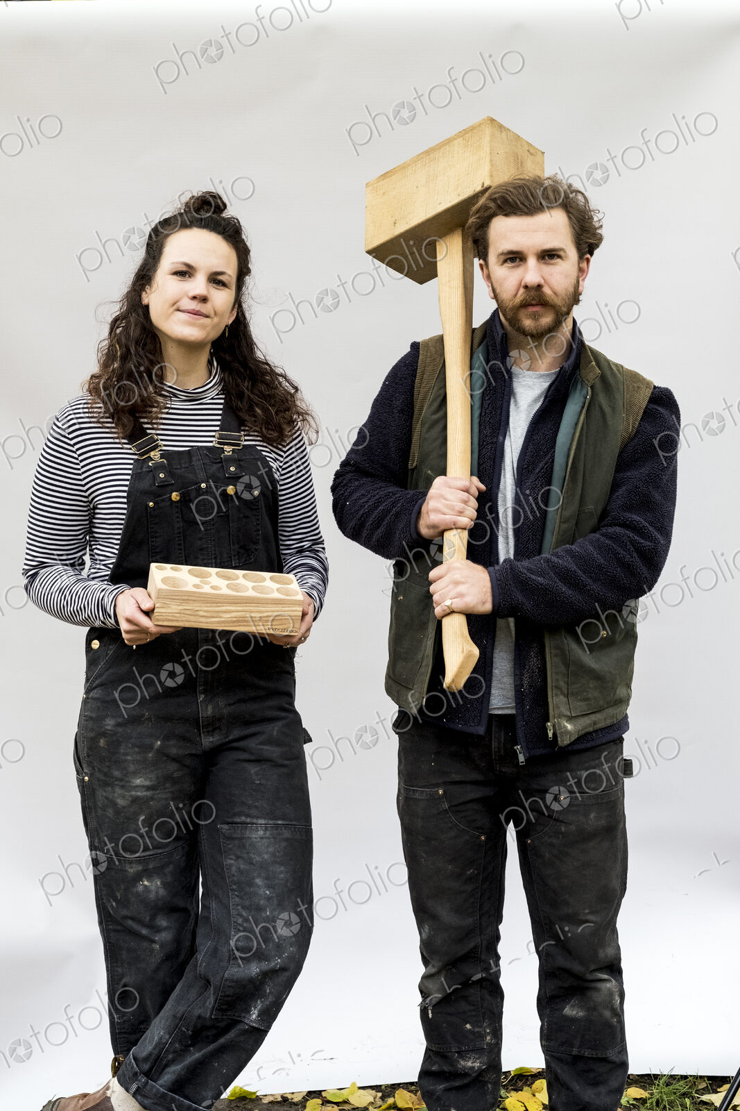 Portrait of woman and bearded man holding wooden blocks standing in front of white…