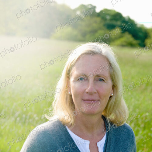 Portrait of woman with blond hair standing outdoors on a meadow, looking at camera. Portrait of woman with blond hair standing outdoors on a meadow, looking at camera.