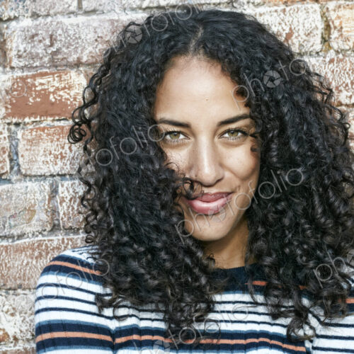 Portrait of young smiling woman with long curly black hair, looking at camera. Portrait of young smiling woman with long curly black hair, looking at camera.