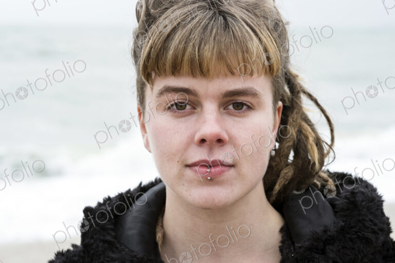 Portrait of young woman with brown hair and dreadlocks and a lip piercing wearing…