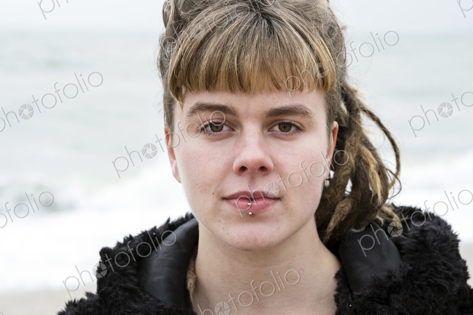 Portrait of young woman with brown hair and dreadlocks and a lip piercing wearing…