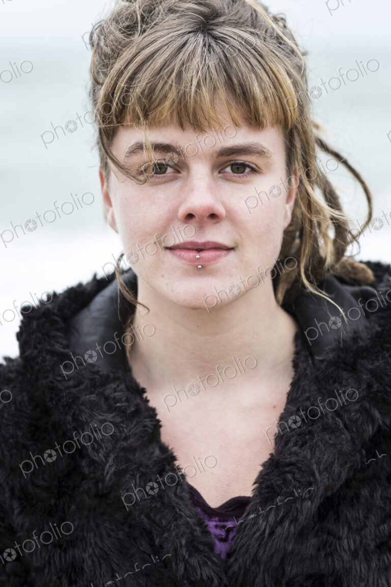 Portrait of young woman with brown hair and dreadlocks and a lip piercing wearing…