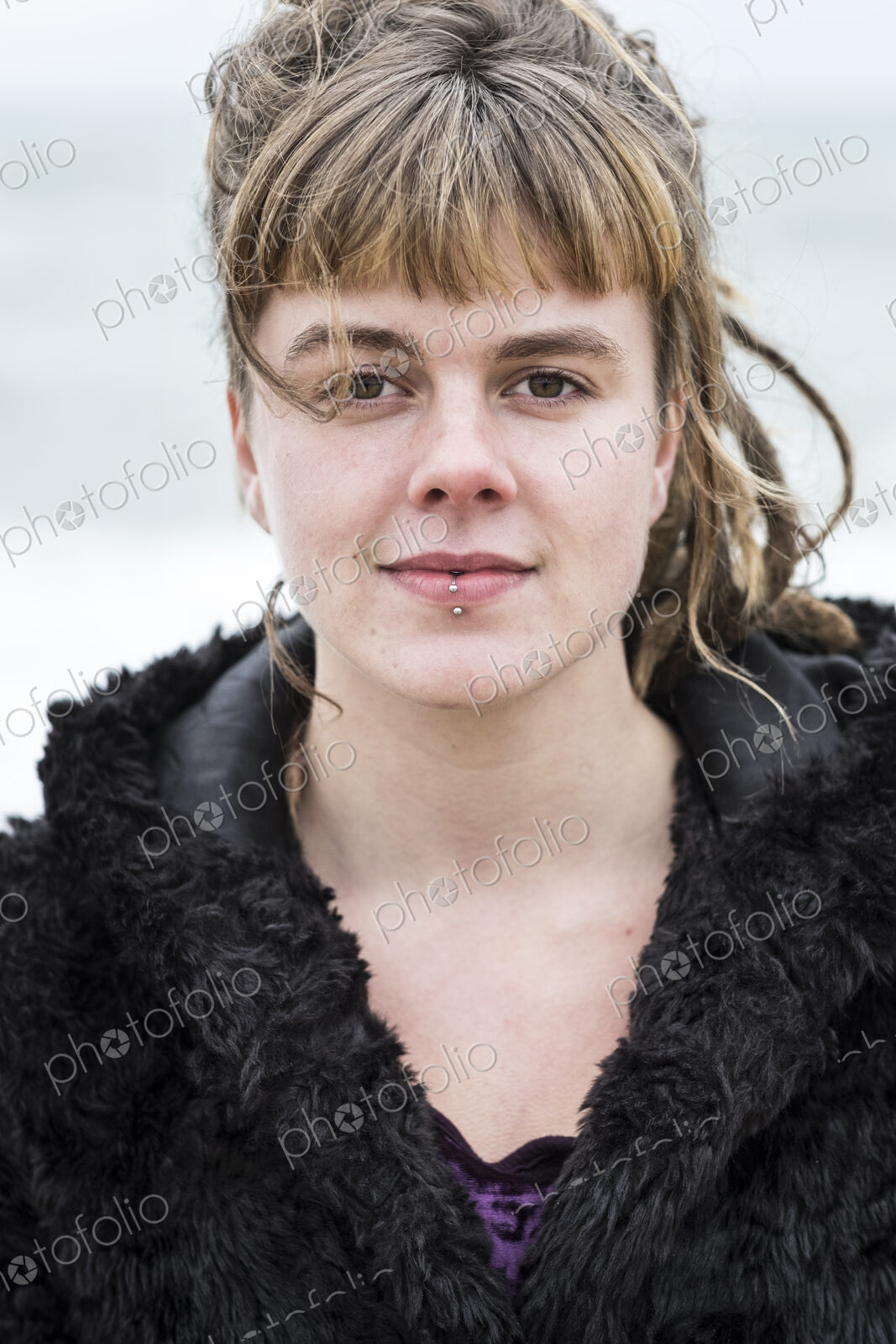 Portrait of young woman with brown hair and dreadlocks and a lip piercing wearing…