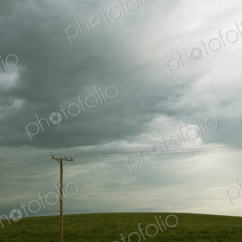 Power lines running through prairie and grassland with cloudy sky above. Power lines running through prairie and grassland with cloudy sky above.