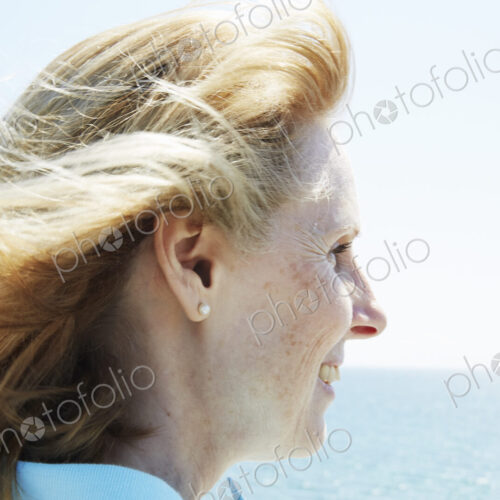 Profile of a blond mature woman standing by the ocean.