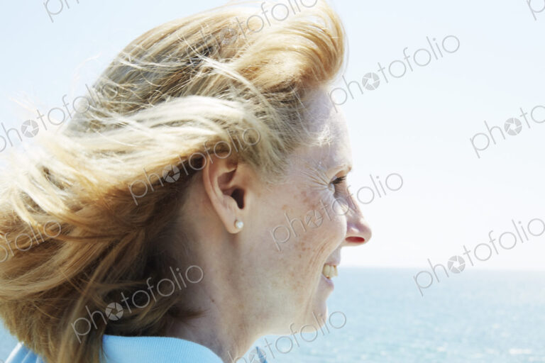 Profile of a blond mature woman standing by the ocean.