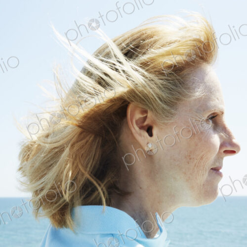 Profile of a blond mature woman standing by the ocean. Profile of a blond mature woman standing by the ocean.