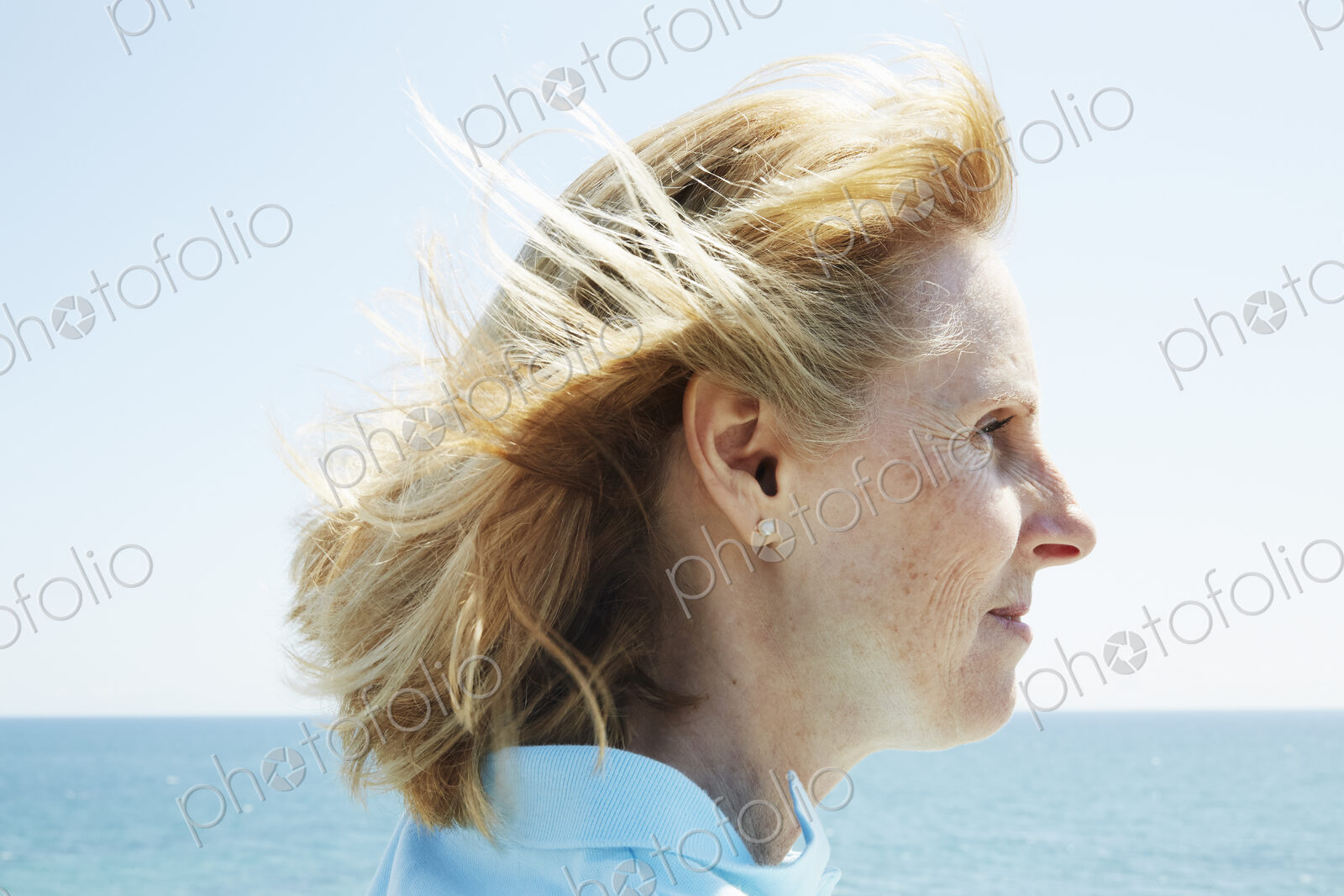Profile of a blond mature woman standing by the ocean.